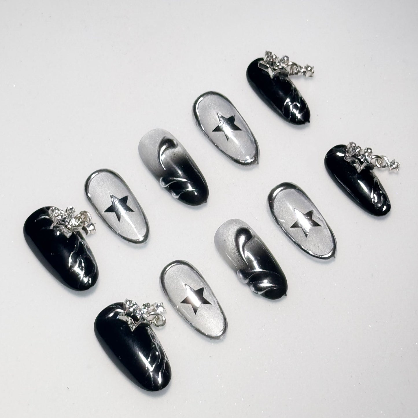 Black and silver nail art designs on a white background