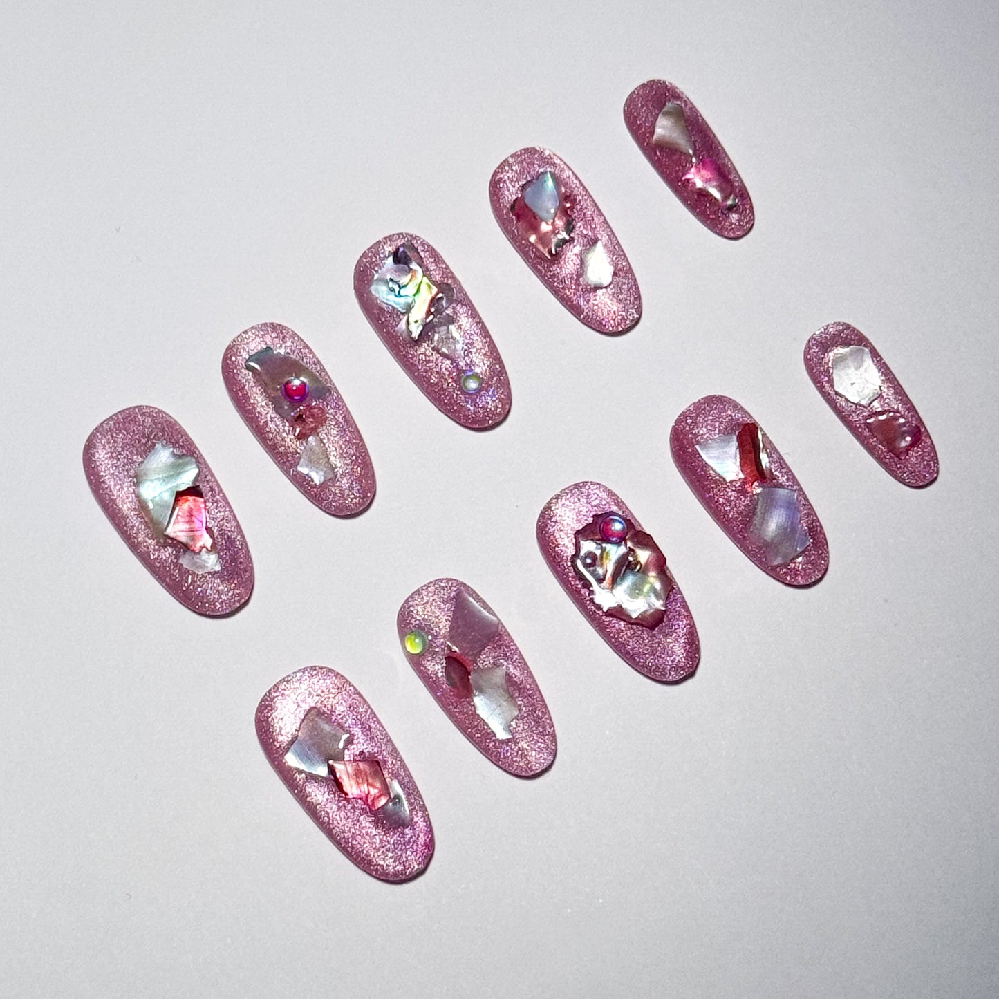 Pink glittery nail art designs with embedded rhinestones on a light gray background