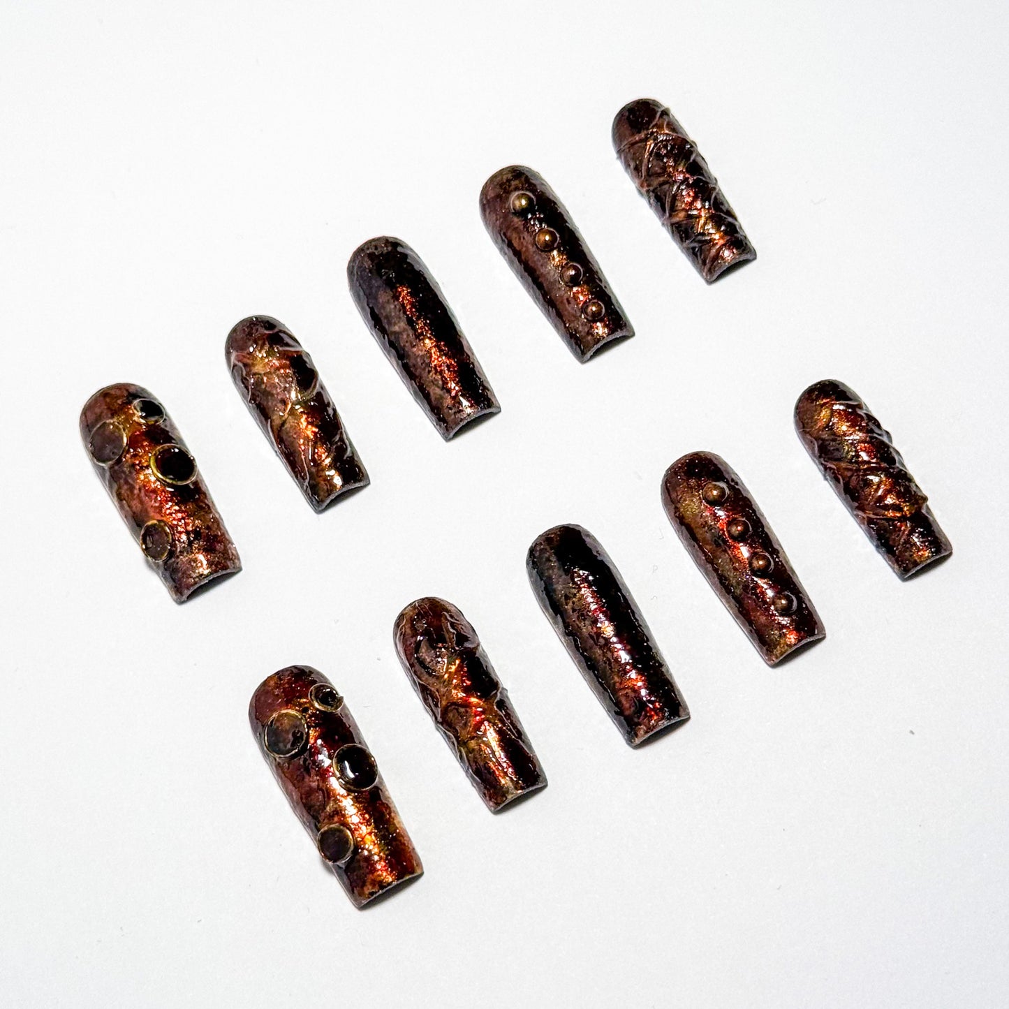 A set of press-on nails art with a metallic finish on a white background