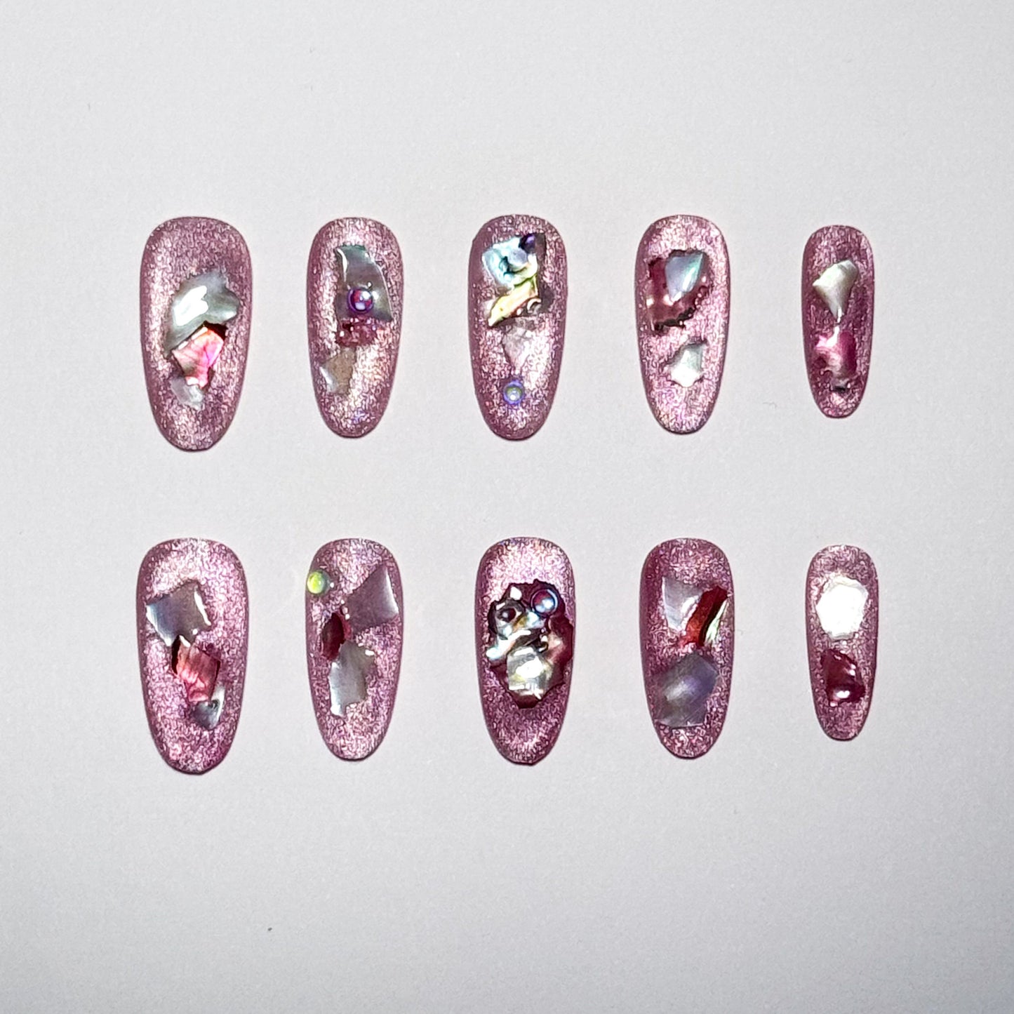 Set of pink nail art designs with rhinestones on a light gray background
