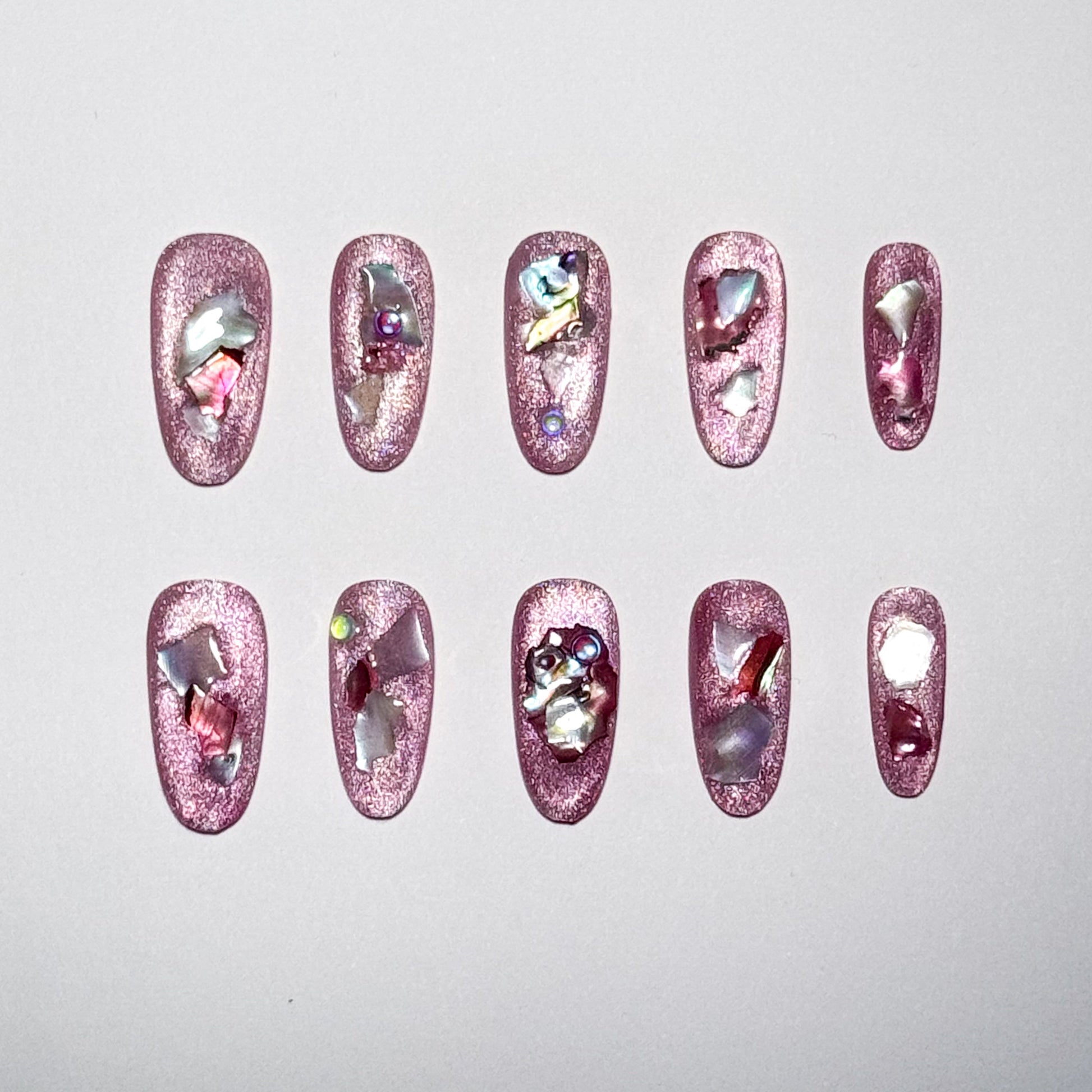 Set of pink nail art designs with rhinestones on a light gray background