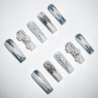 Set of decorative nails with marble effect and floral designs on a light gray background