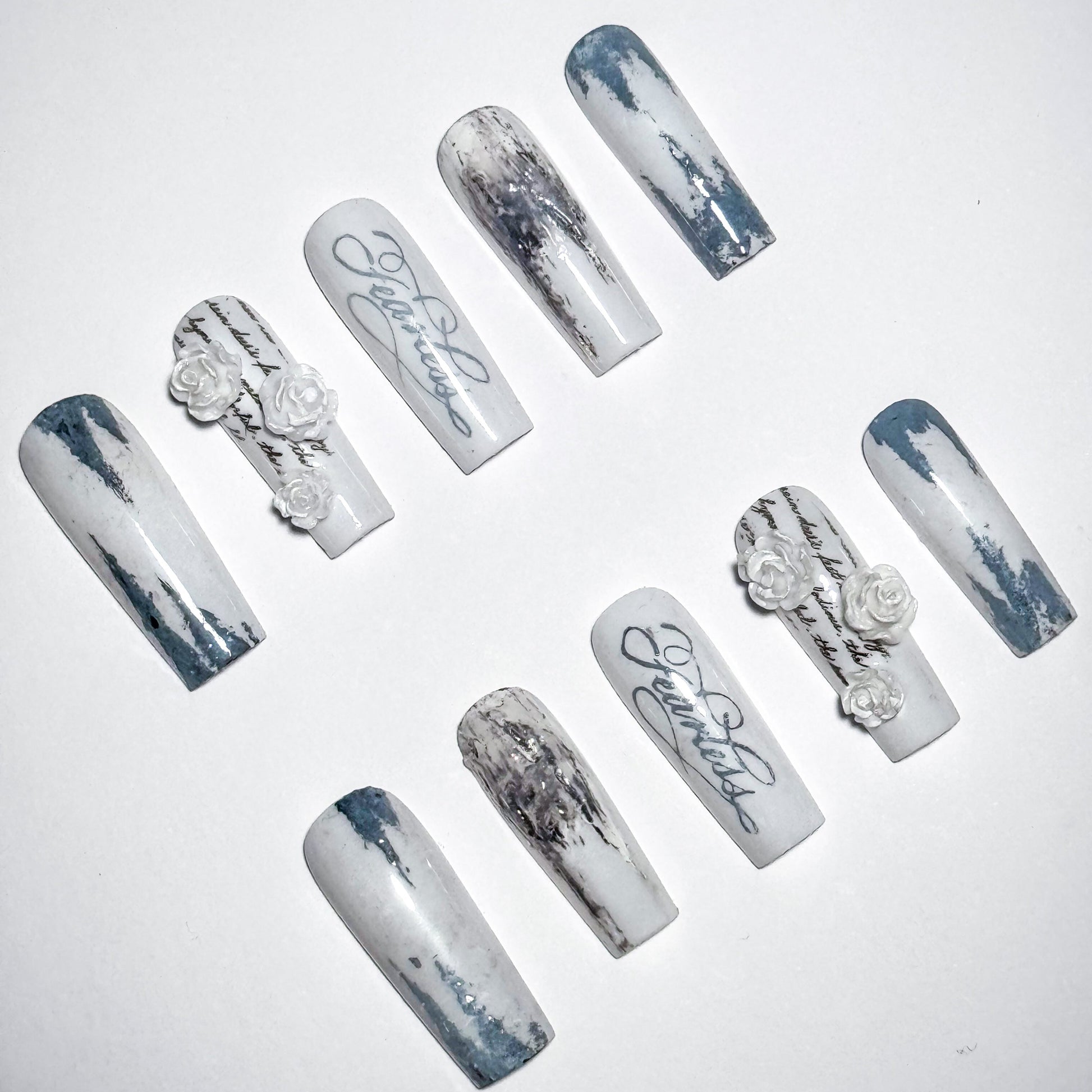 Set of decorative nails with marble effect and floral designs on a white background