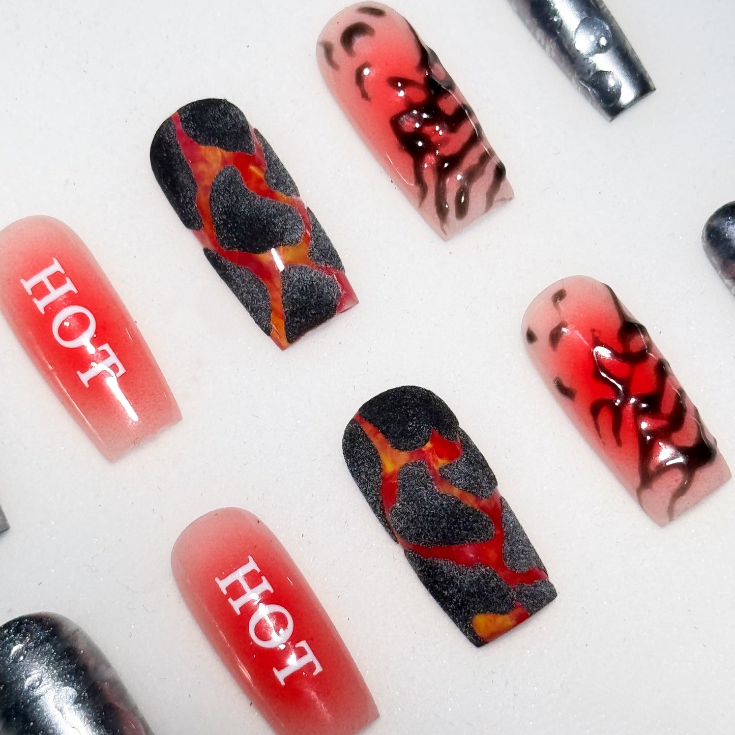 Nail art with red, black, and silver design on a white background