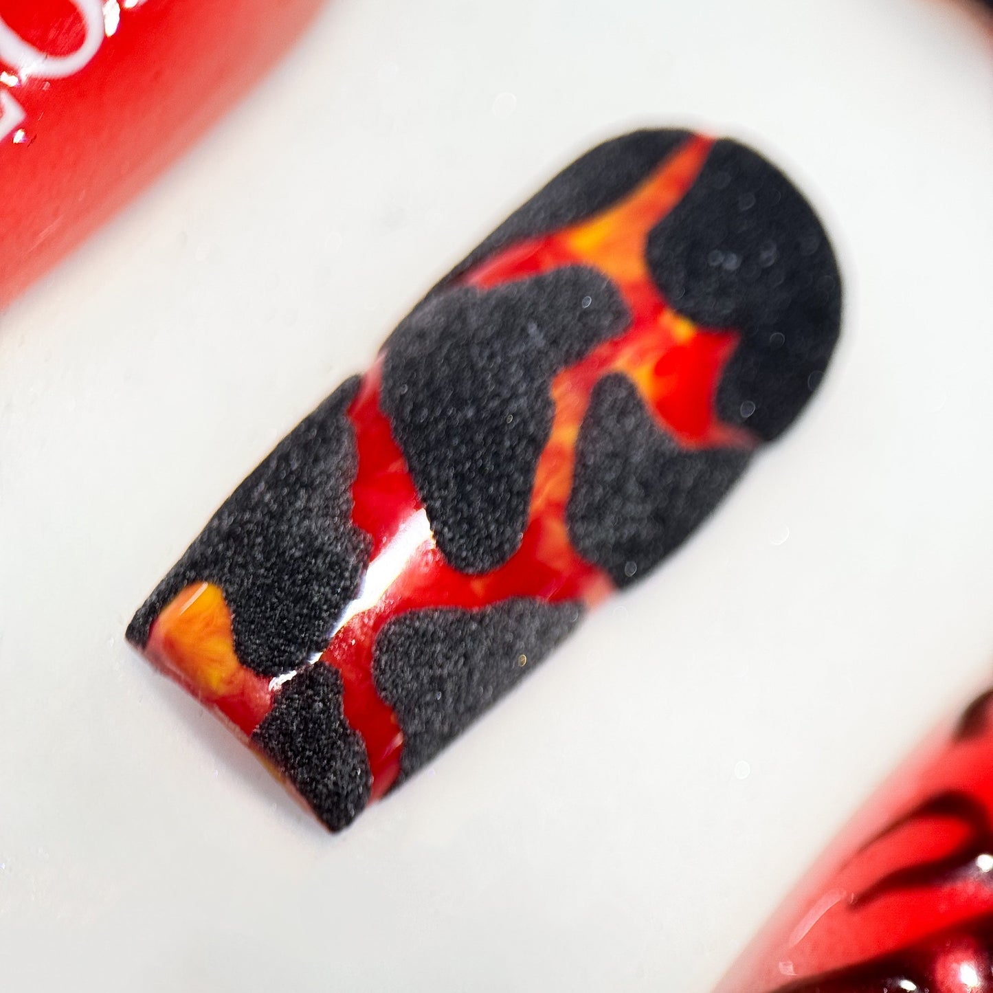 Close-up of a red and black patterned nail on a white background