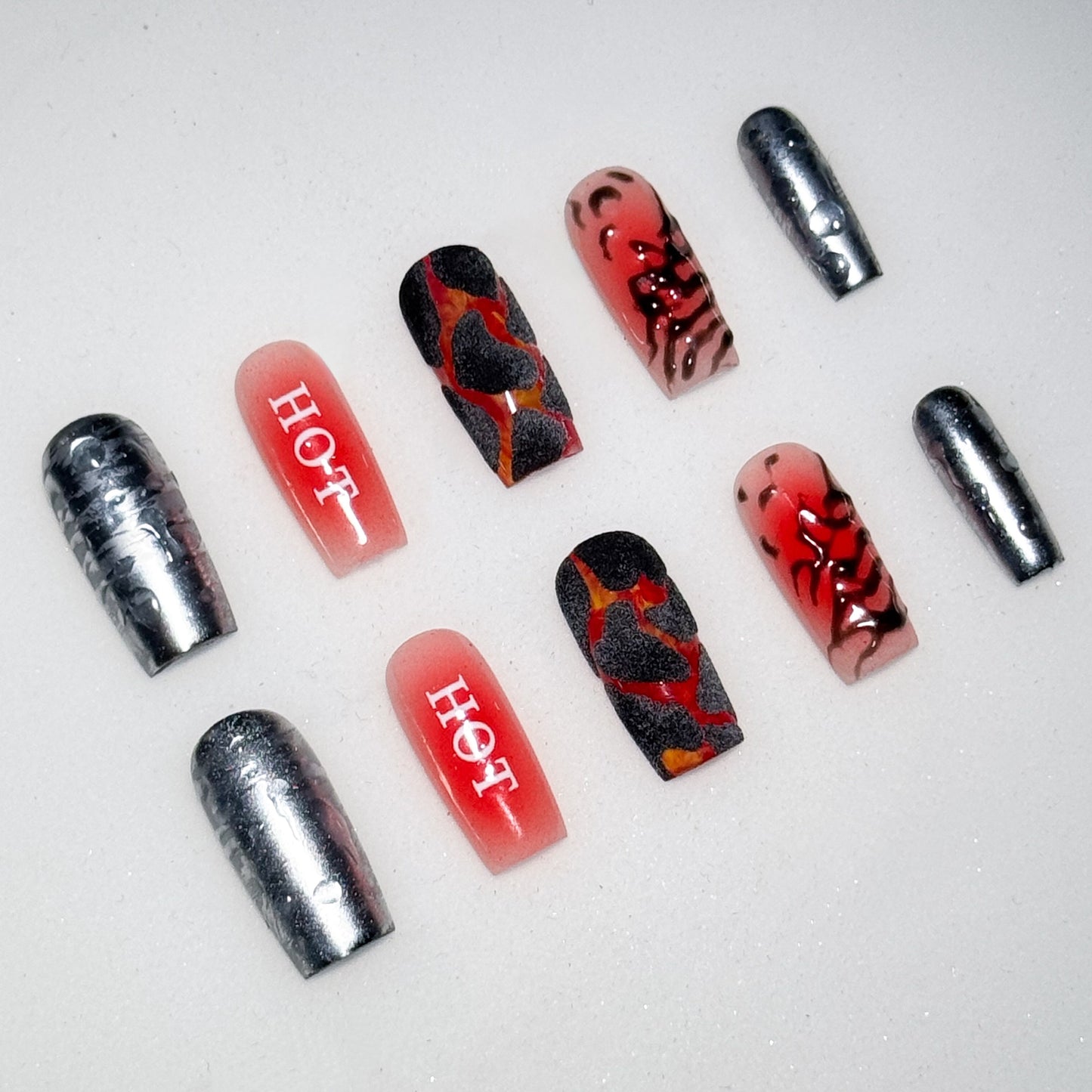 Nail art with red, black, and silver design on a white background