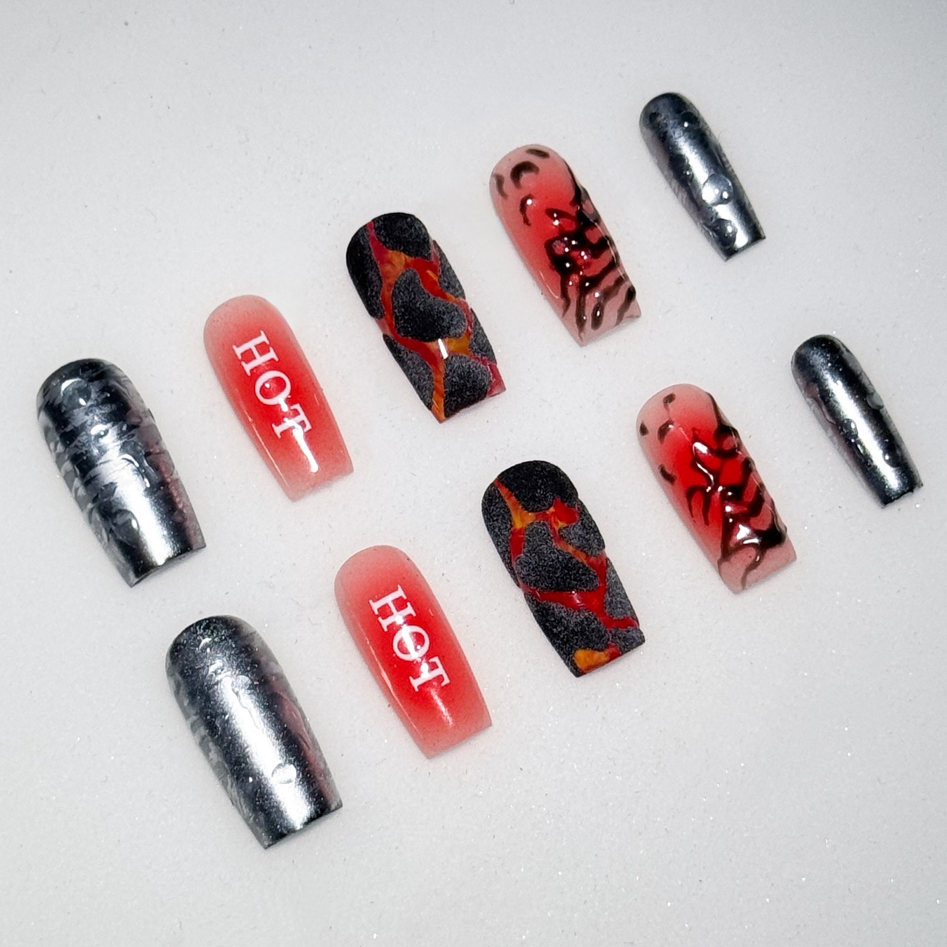 Nail art with red, black, and silver design on a white background