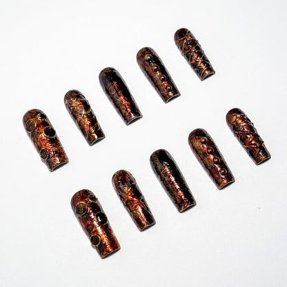 A set of press-on nails art with a metallic finish on a white background